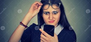 mujer confusa con los vidrios que tienen problema que ve el telefono celular 80364645